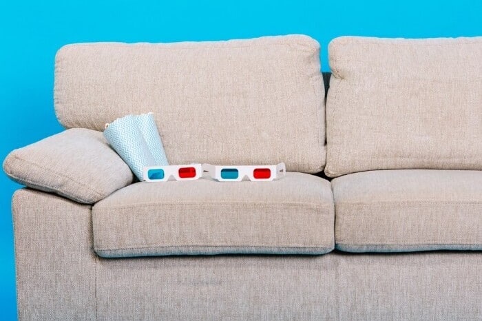 cómodo sofá con gafas 3d palomitas maíz sobre fondo azul