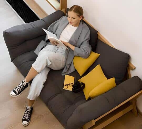 mujer en sofá cama leyendo libro vista cenital